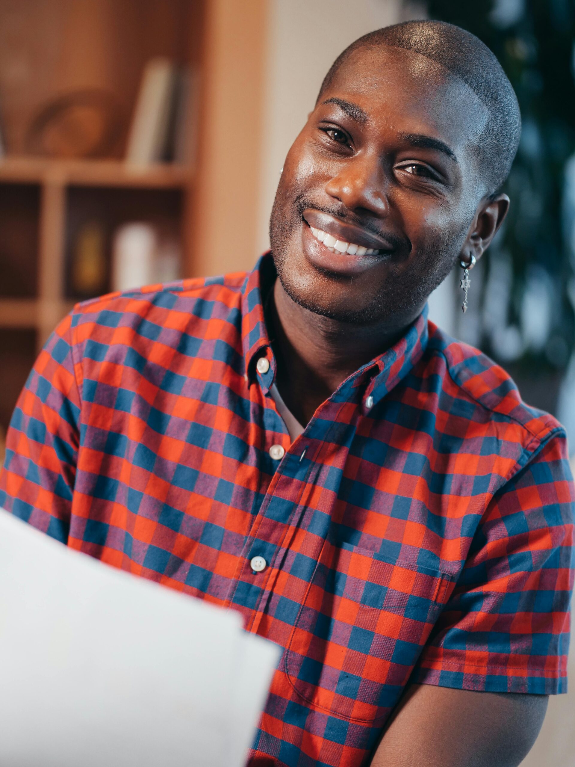 Portrait of a smiling man in a checkered shirt working indoors.